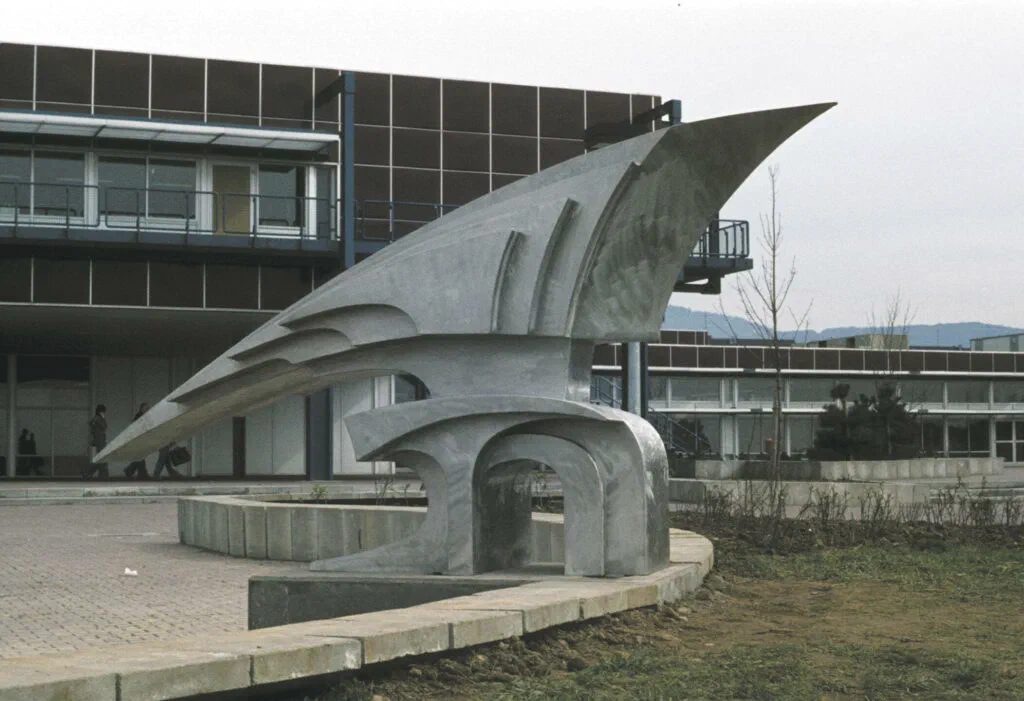 Schönberger Rutsche, Dreiviertelansicht vor dem Schulgebäude, Skulptur, Edelstahl