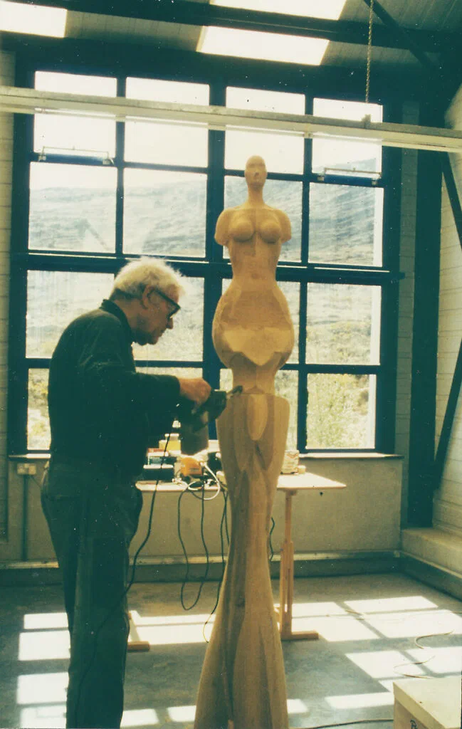 Stele der Fortuna, Werkstattfoto: der Künstler bearbeitet die Holzfigur mit einem Elektrowerkzeug im Atelier